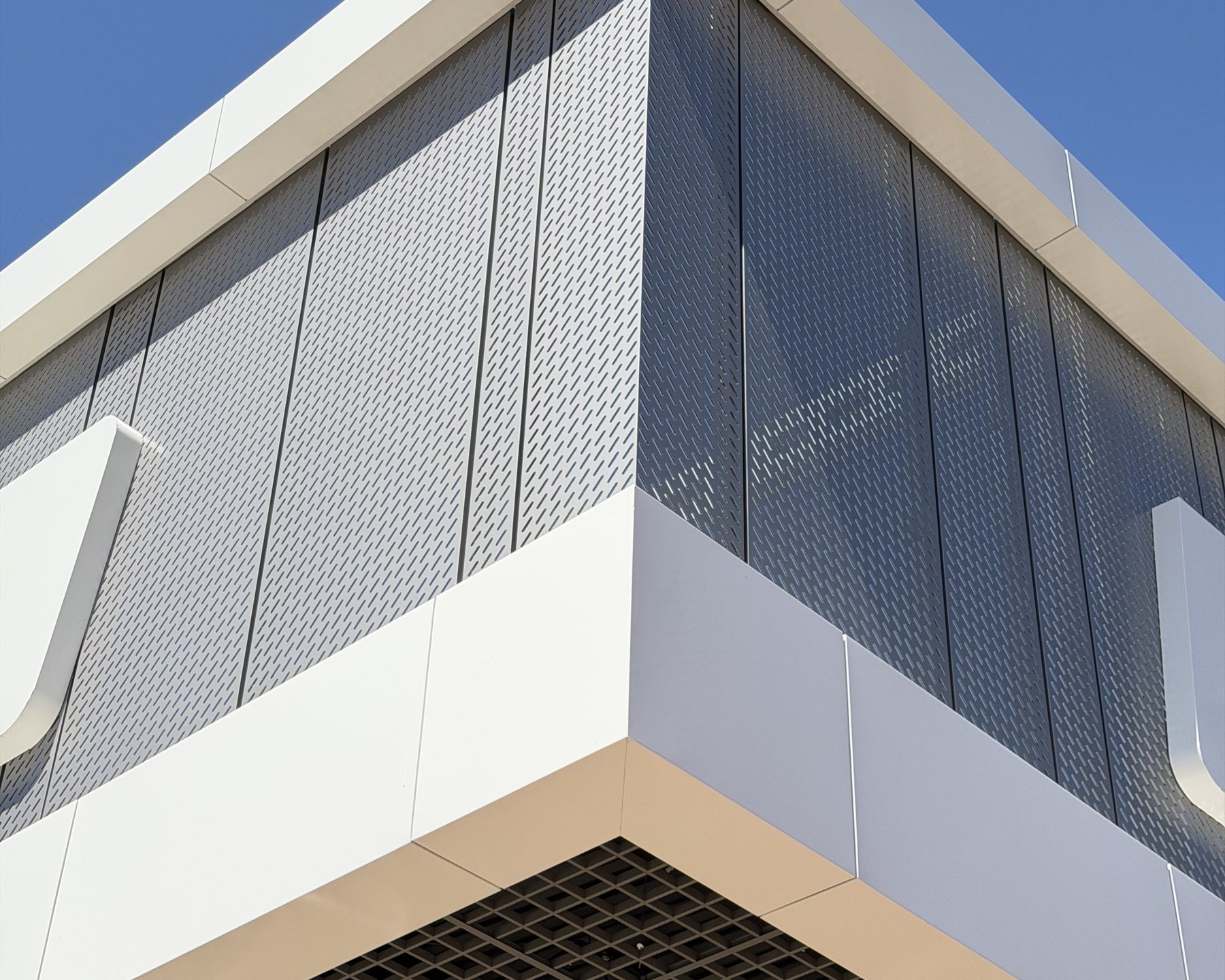 White ACM folded around the corner of a building, with a soffit grid below
